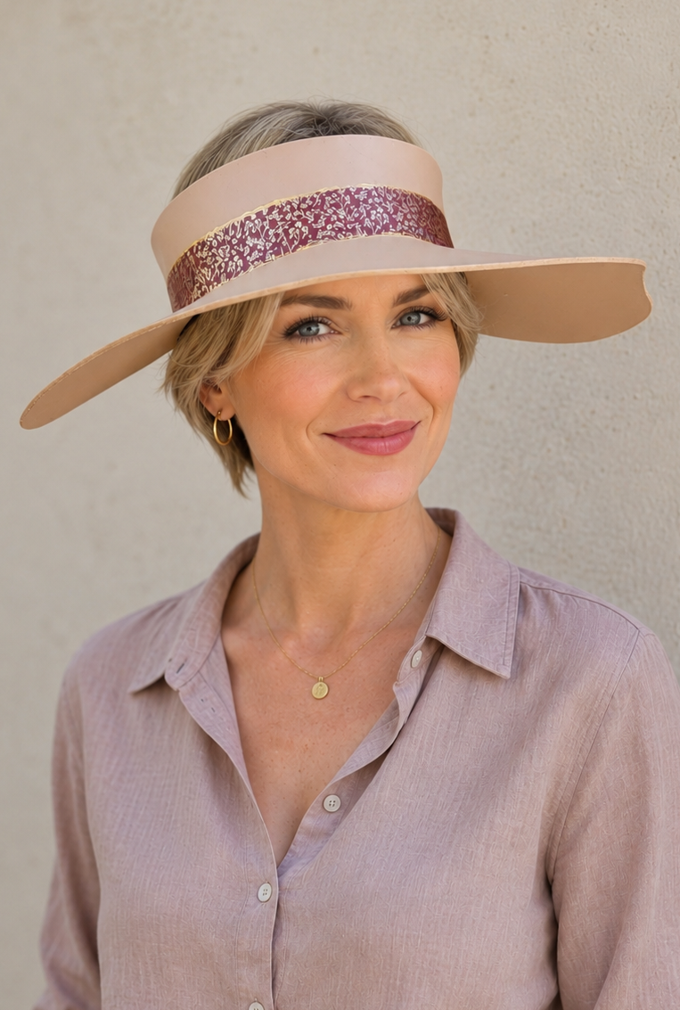 Woman wearing a wide-brimmed hat with a decorative band against a plain background