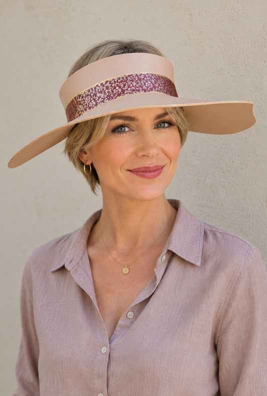 Woman wearing a wide-brimmed hat with a decorative band against a plain background