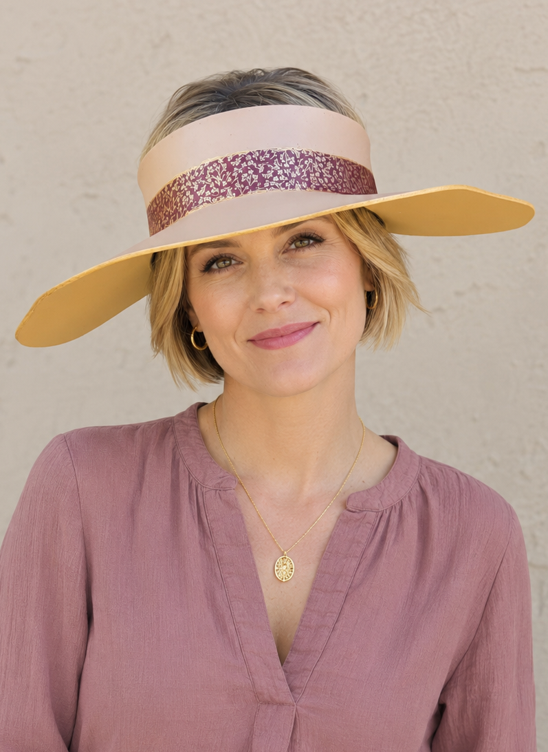 Woman wearing a wide-brimmed hat with a decorative band against a plain background