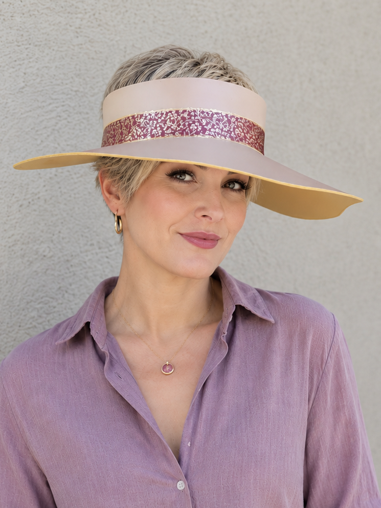 Woman wearing a wide-brimmed hat with a visor against a plain background