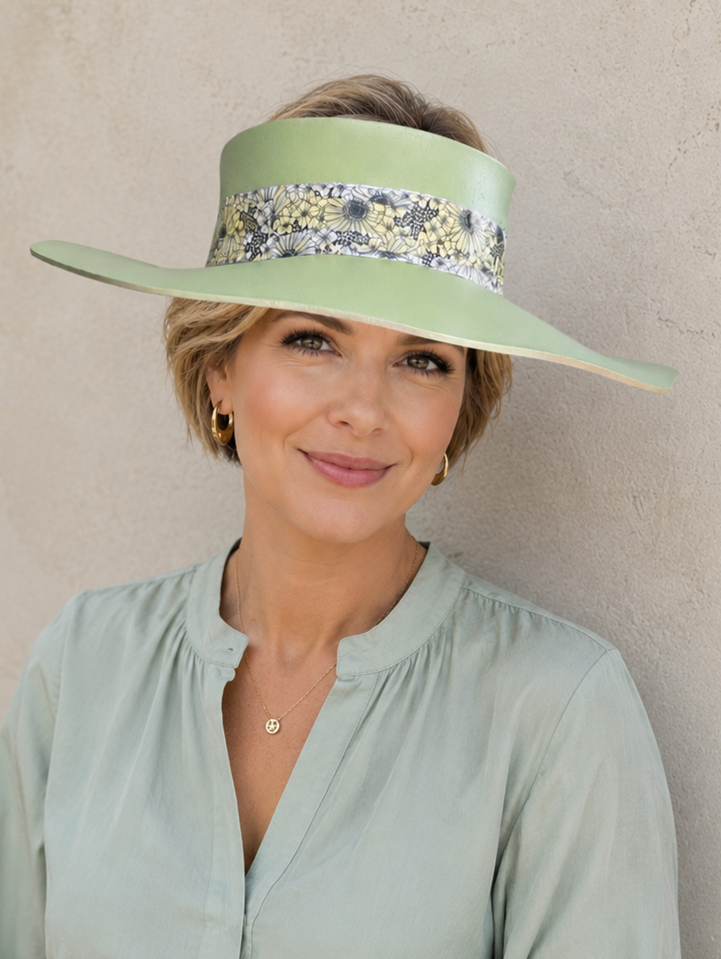 Woman wearing a light green visor with floral band against a beige background
