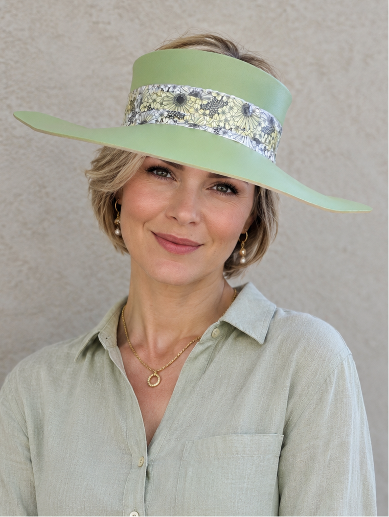 Woman wearing a light green visor with decorative band against a neutral background