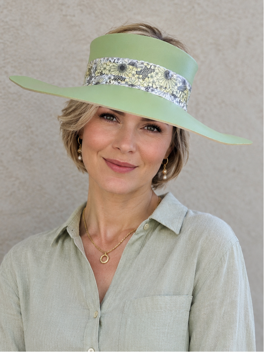 Woman wearing a light green visor with decorative band against a neutral background