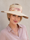 Woman wearing a wide-brimmed hat with floral band against a neutral background