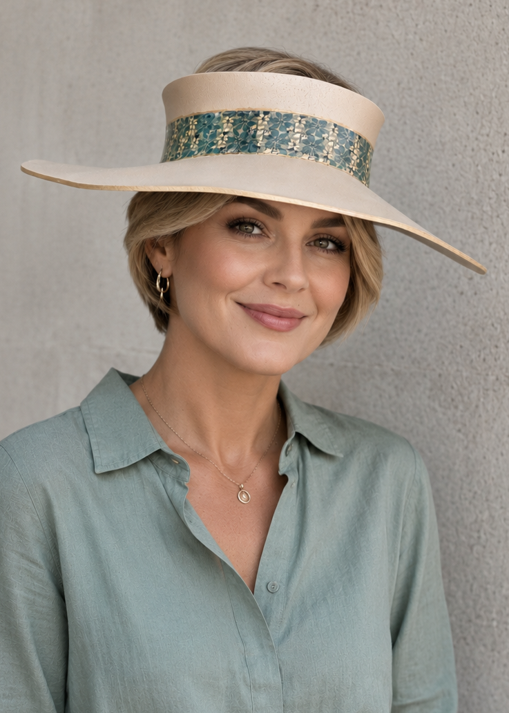 Woman wearing a wide-brimmed hat with a decorative band against a plain background