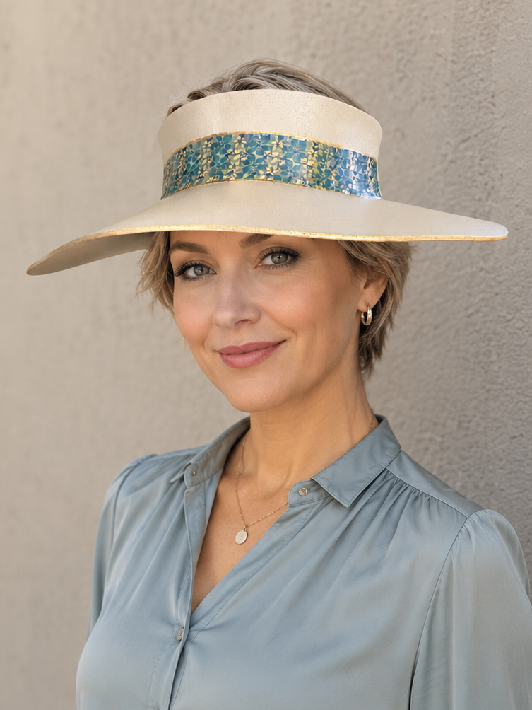 Woman wearing a wide-brimmed hat with a decorative band against a plain background