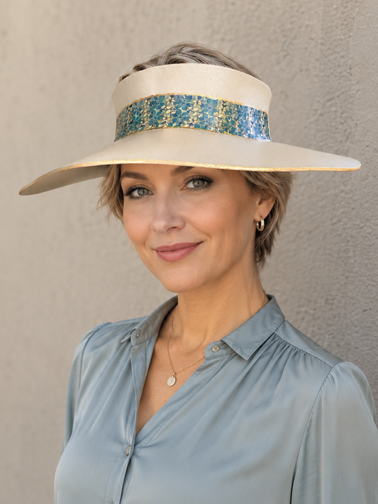 Woman wearing a wide-brimmed hat with a decorative band against a plain background