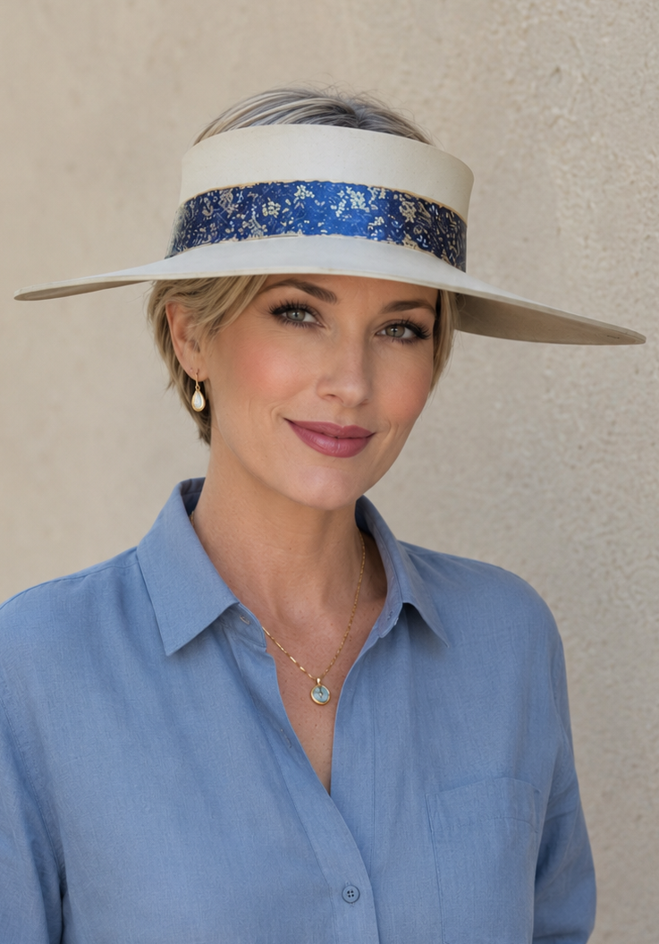 Woman wearing a wide-brimmed hat with a blue band against a beige background