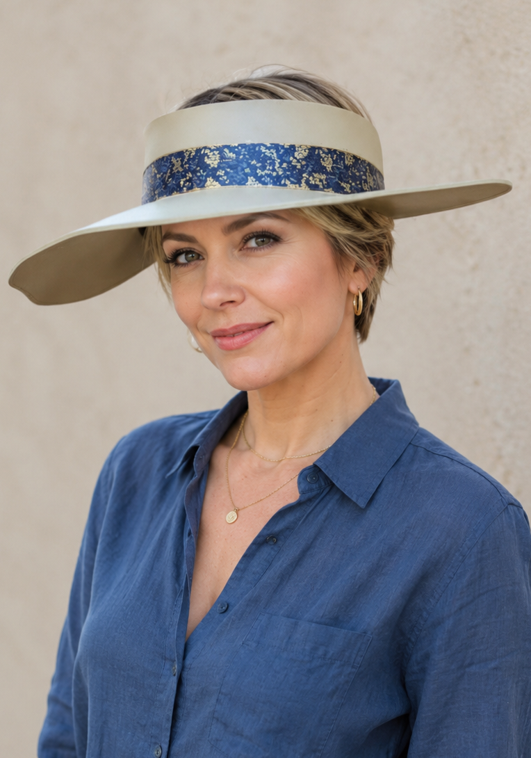 Woman wearing a blue shirt and wide-brimmed hat with a floral band against a neutral background