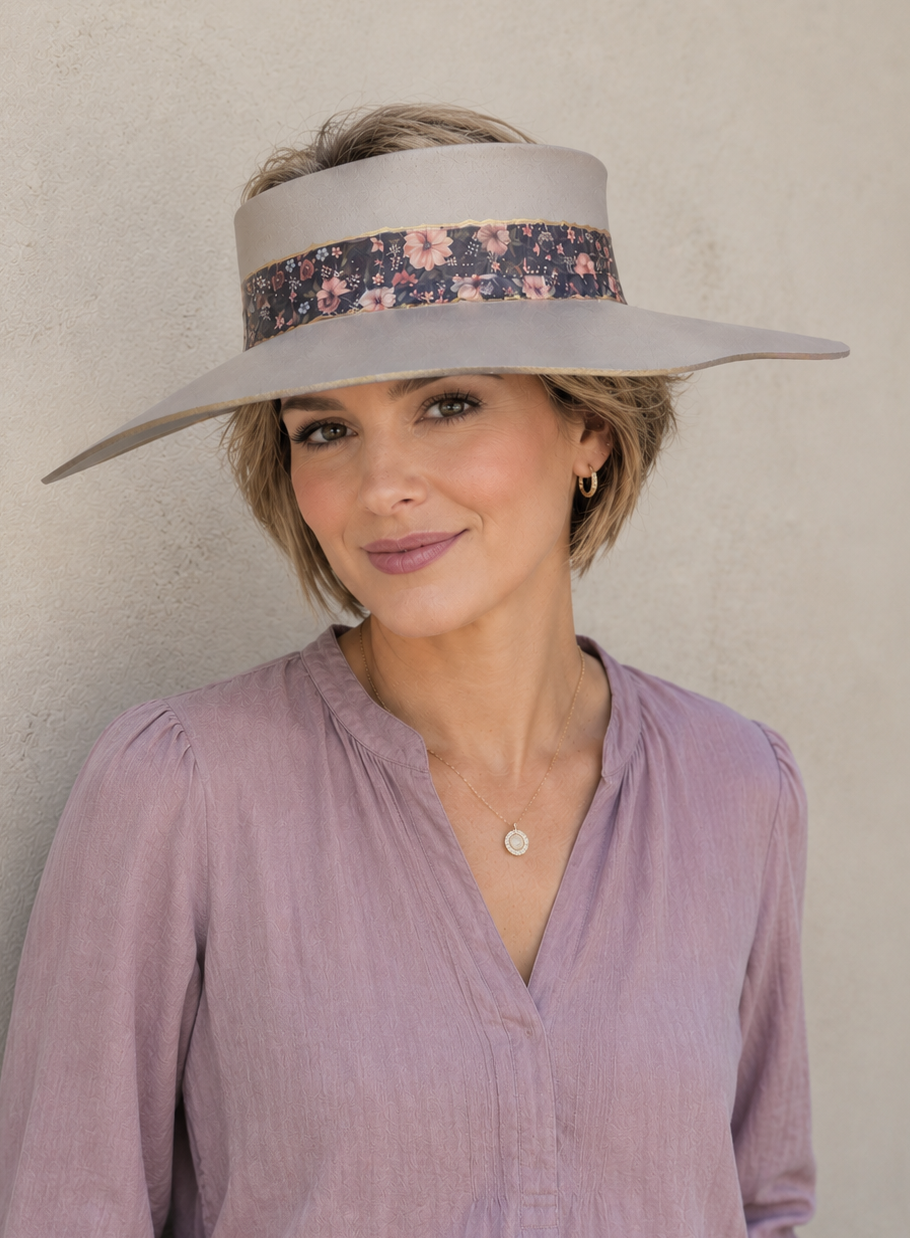 Woman wearing a wide-brimmed hat with floral band against a plain background