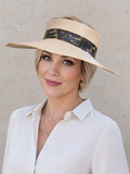 Woman wearing a beige visor hat with a black band against a light background