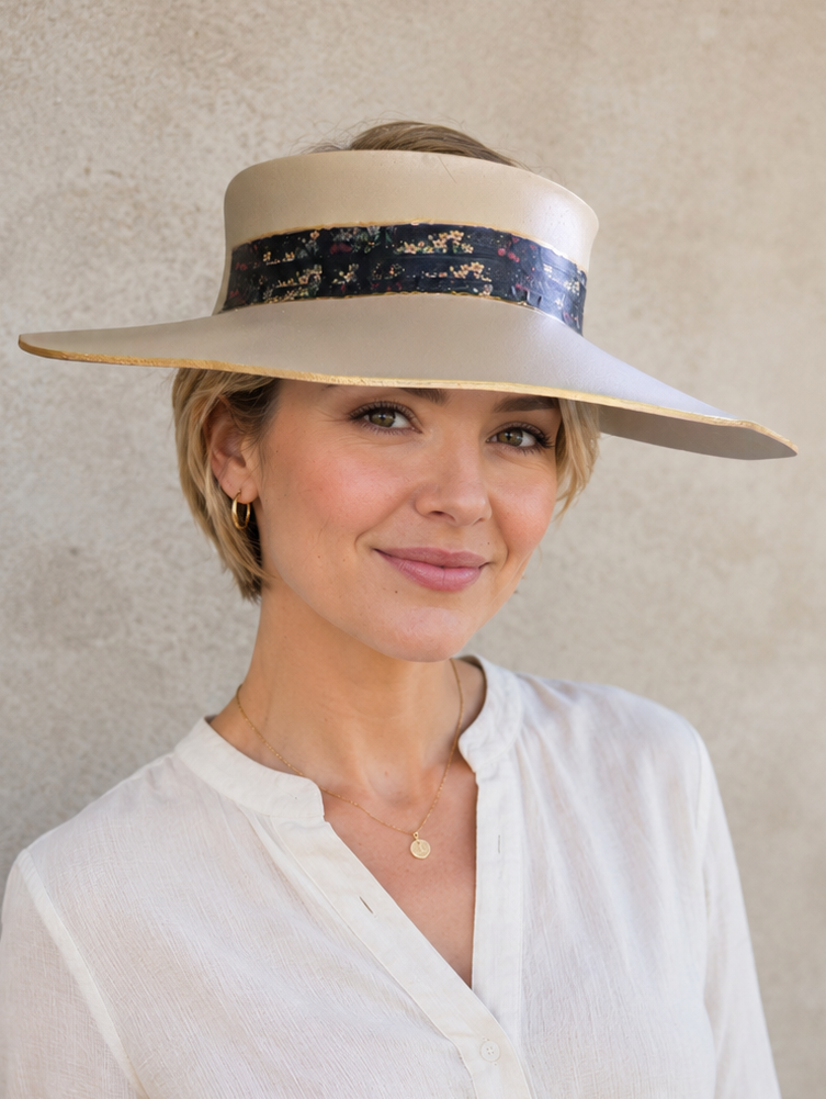 Woman wearing a wide-brimmed hat with a decorative band against a plain background