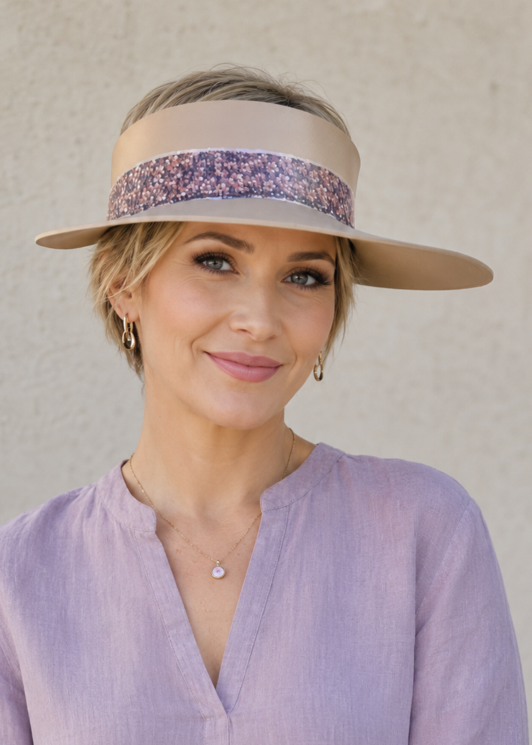 Woman wearing a light purple blouse and a visor with a floral band against a plain background