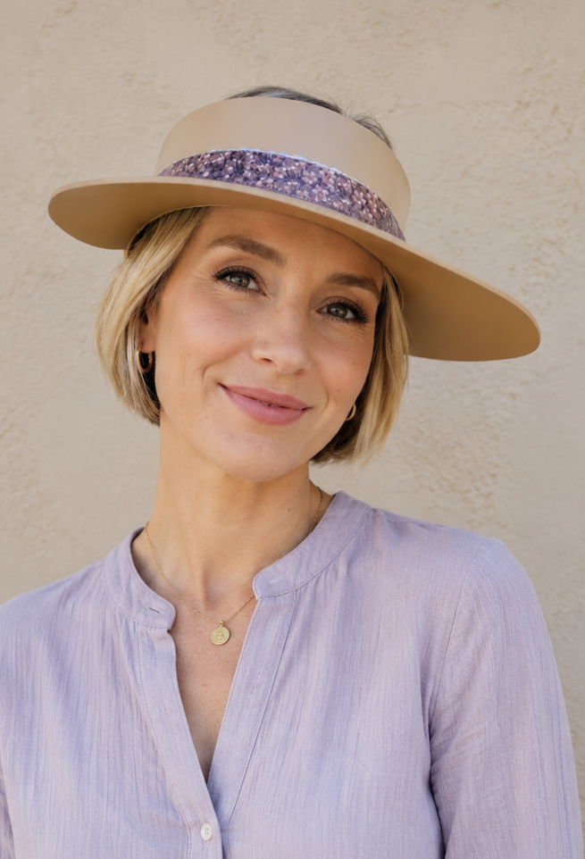 Woman wearing a light purple shirt and beige hat against a plain background