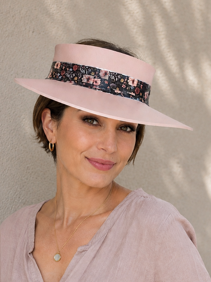 Woman wearing a pink visor and light pink shirt against a beige wall
