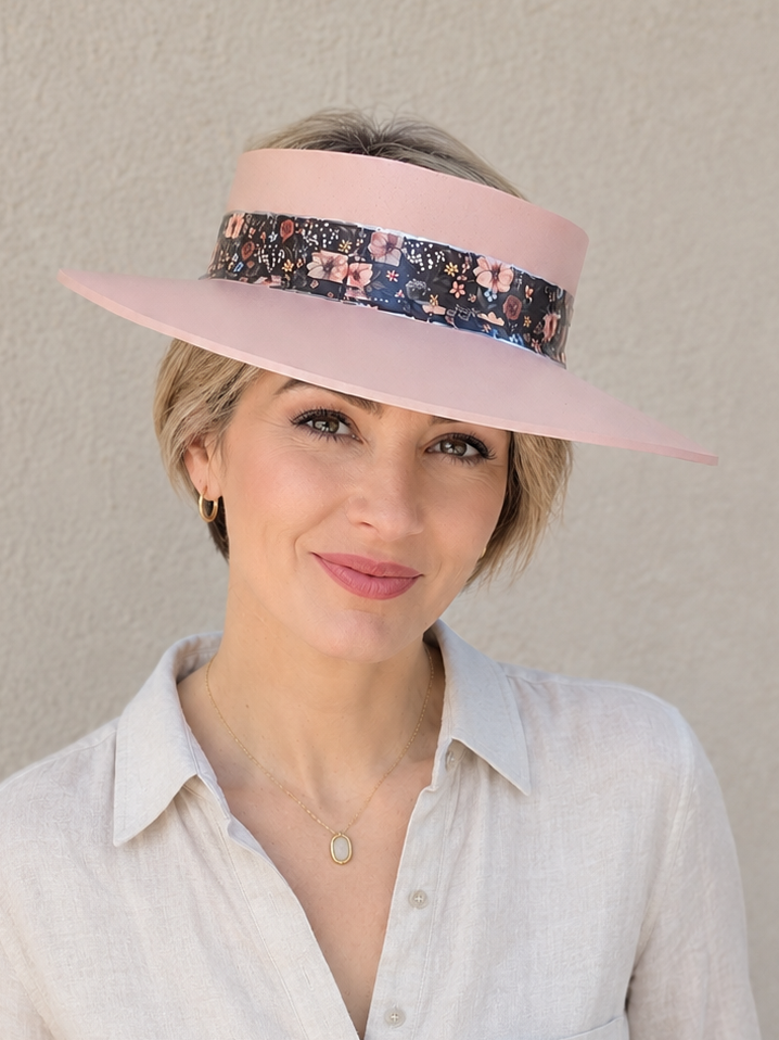 Woman wearing a wide-brimmed visor with a floral band against a plain background