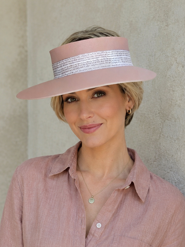 Woman wearing a pink visor and matching shirt against a beige wall