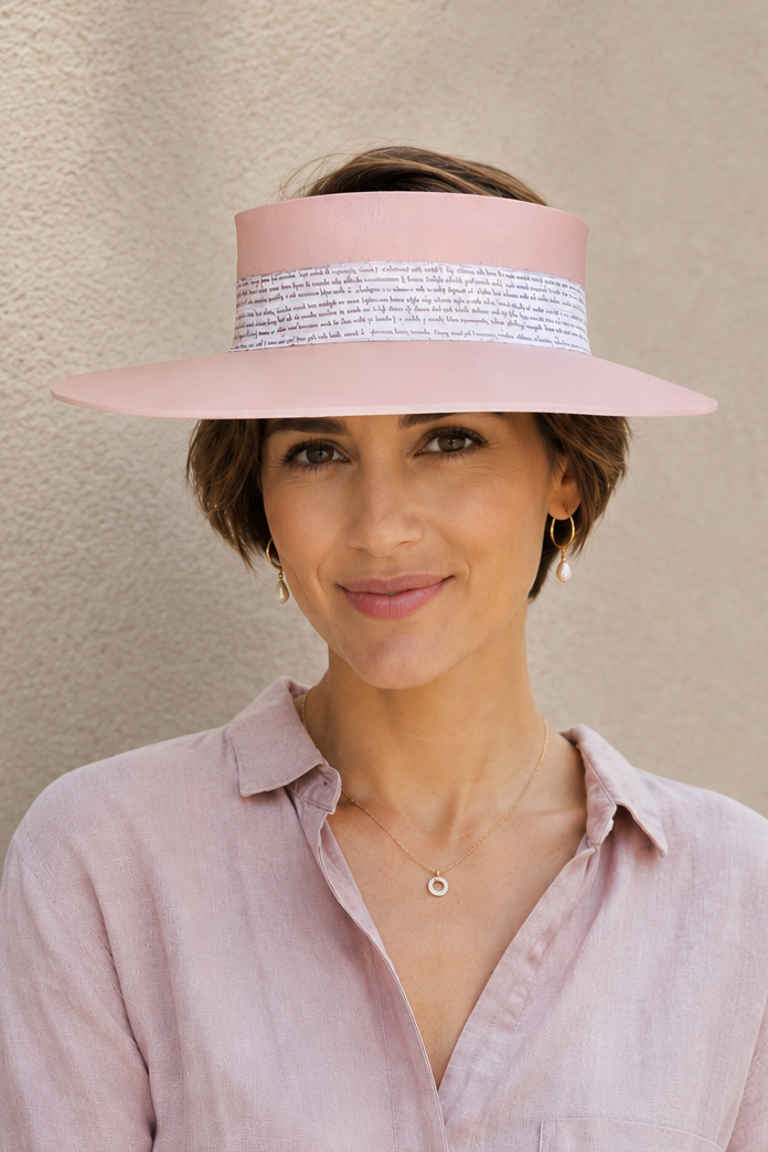 Woman wearing a pink hat and matching shirt against a beige background