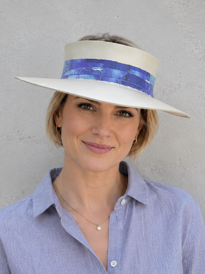 Woman wearing a wide-brimmed hat with a blue band against a gray background
