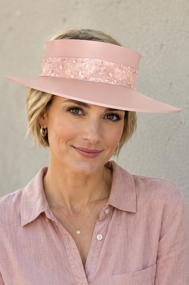 Woman wearing a pink visor and matching shirt against a plain background