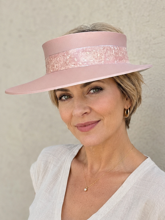 Woman wearing a pink visor hat against a plain background