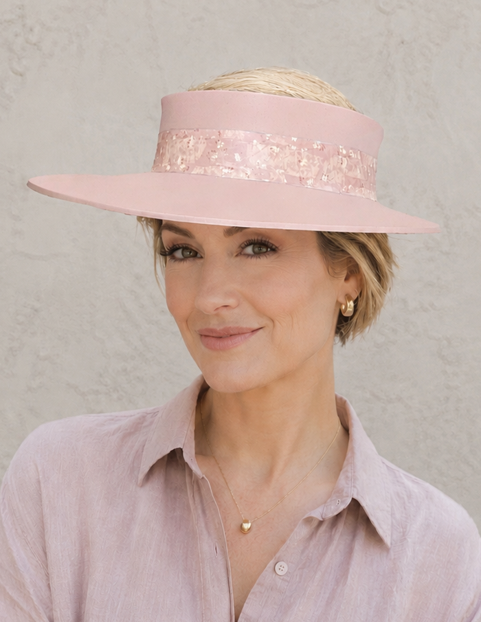 Woman wearing a pink hat and matching shirt against a plain background