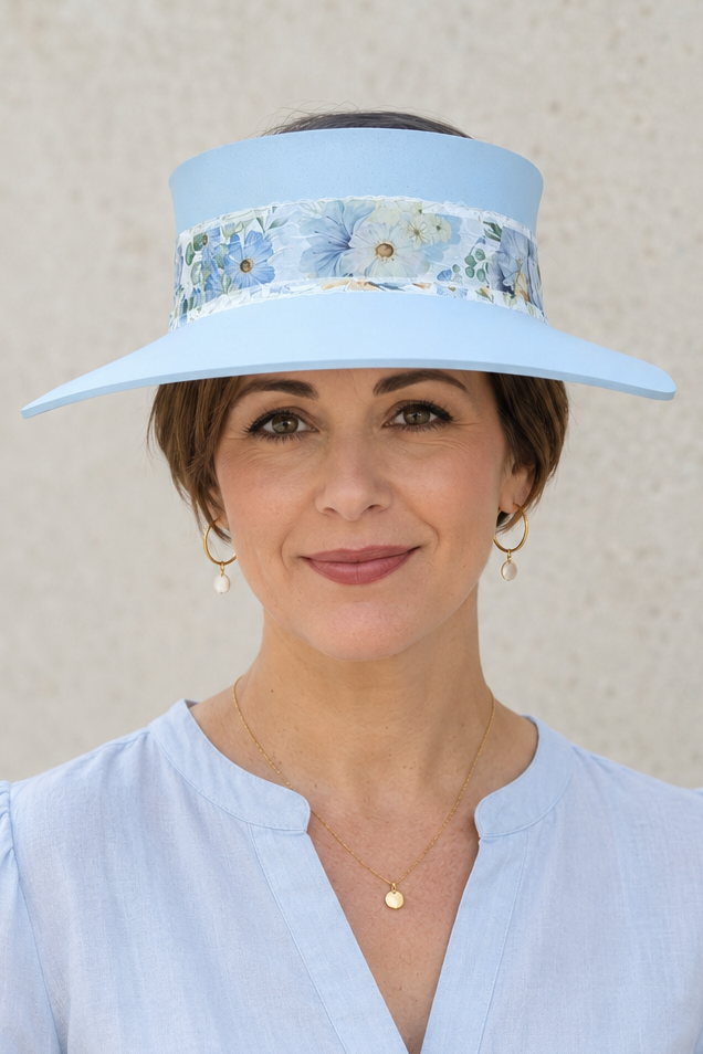 Woman wearing a light blue visor hat with floral band against a neutral background