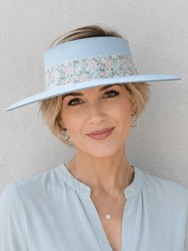 Woman wearing a light blue visor and matching blouse against a plain background