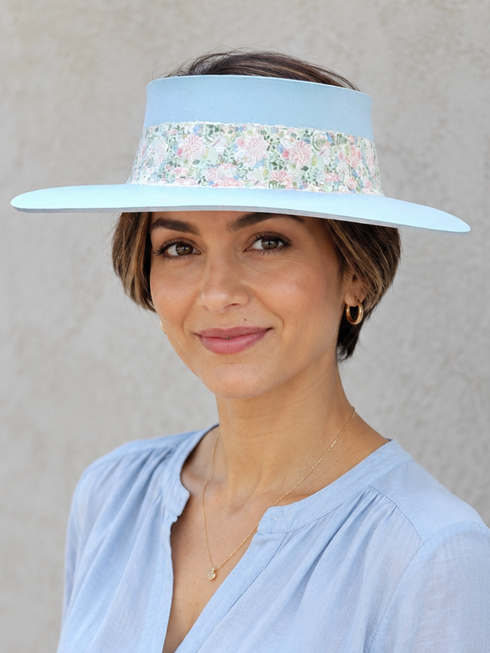 Woman wearing a light blue visor with floral band against a plain background