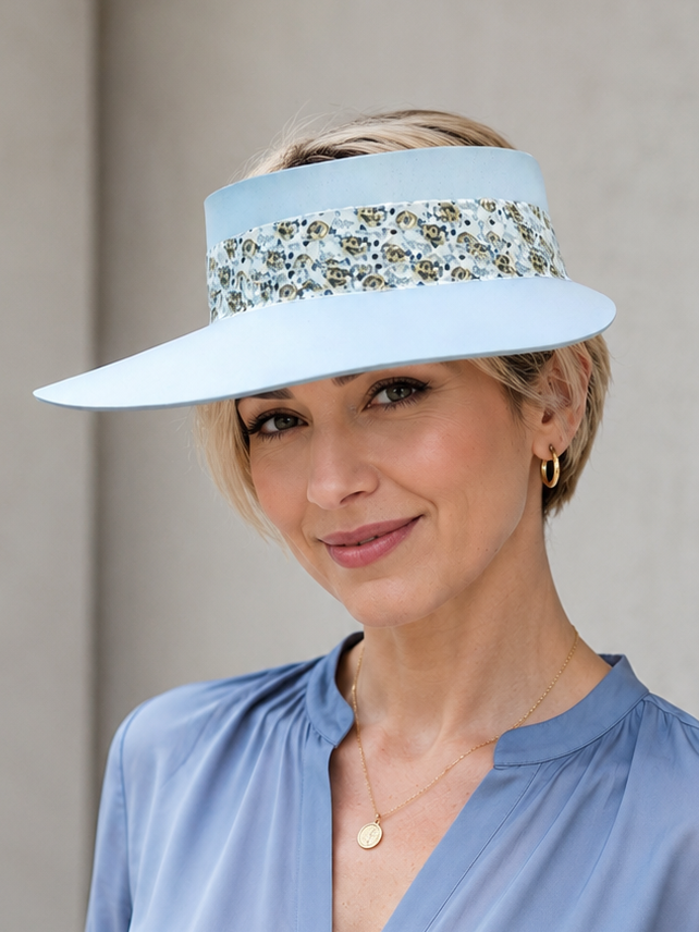 Woman wearing a light blue visor and matching blouse against a neutral background