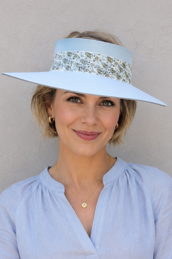 Woman wearing a light blue visor hat and matching blouse against a beige background