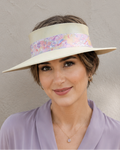 Woman wearing a wide-brimmed hat with a floral band against a neutral background