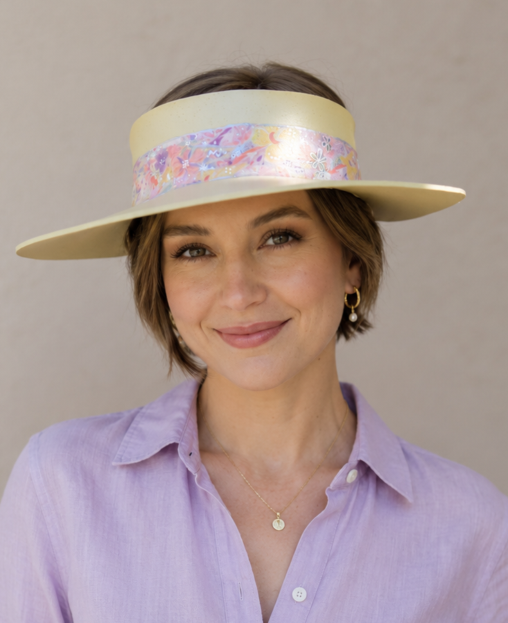 Woman wearing a wide-brimmed hat with a colorful band against a plain background