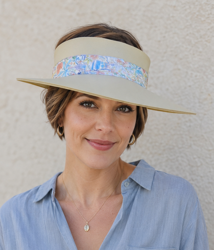 Woman wearing a wide-brimmed hat with a floral band against a plain background