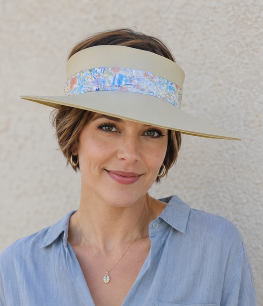 Woman wearing a wide-brimmed hat with a floral band against a plain background