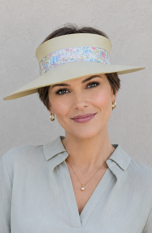 Woman wearing a light blue shirt and beige visor against a gray background