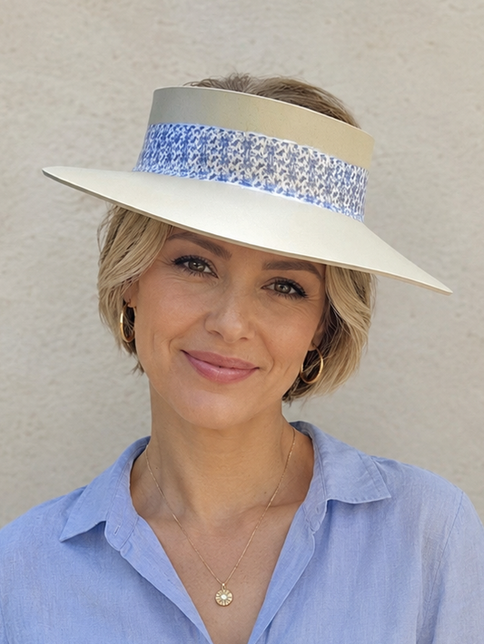 Woman wearing a light blue shirt and a white visor with a decorative band against a beige background