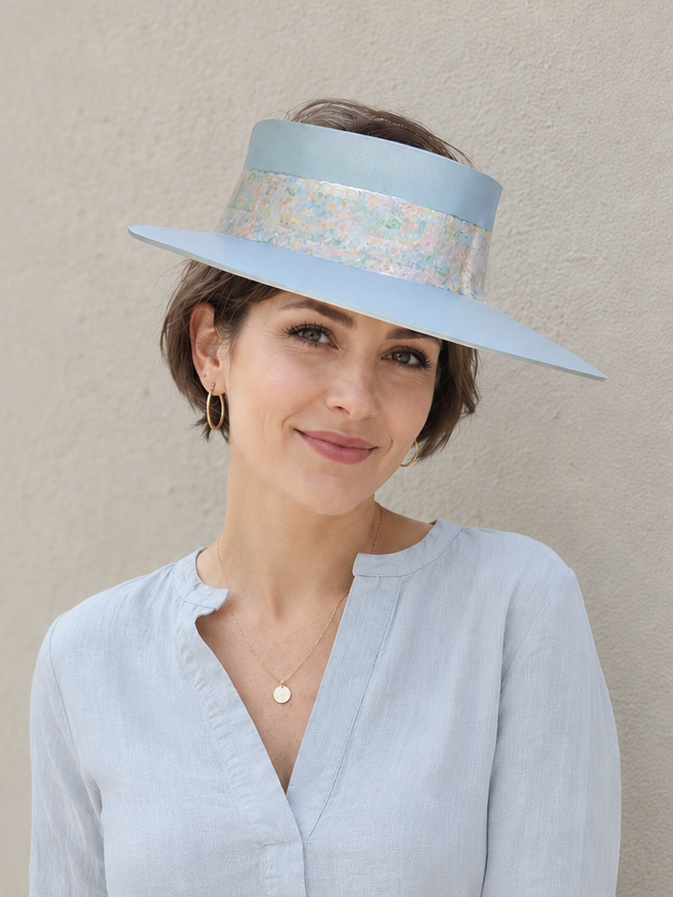 Woman wearing a light blue visor and matching shirt against a beige background