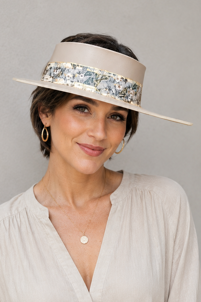 Woman wearing a beige hat with a decorative band against a gray background