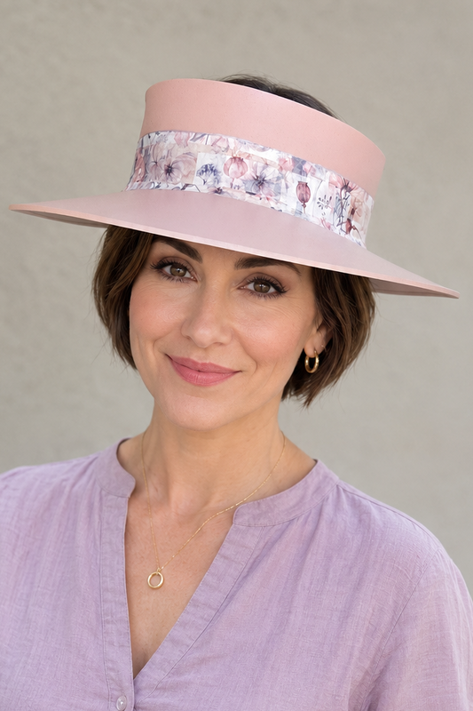 Woman wearing a light purple top and a decorative hat against a plain background