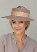 Woman wearing a wide-brimmed hat with a gold band against a plain background