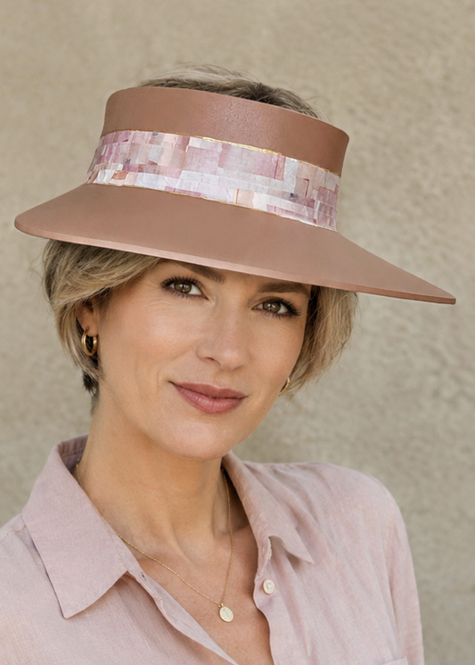 Woman wearing a wide-brimmed hat and light pink shirt against a beige background
