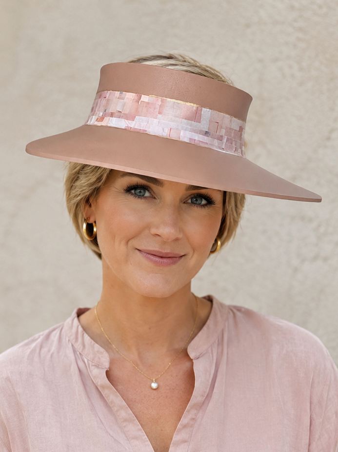 Woman wearing a pink visor hat and light pink shirt against a beige background