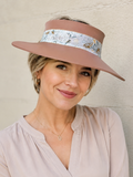 Woman wearing a wide-brimmed hat with a floral band against a plain background
