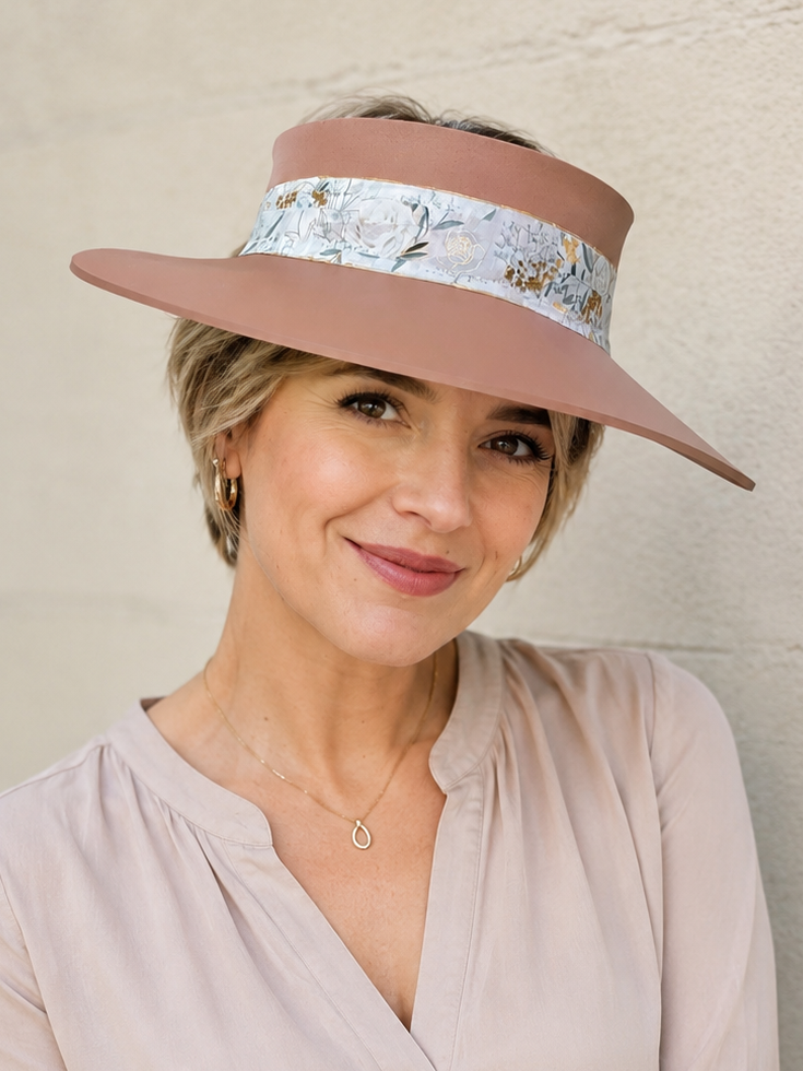 Woman wearing a wide-brimmed hat with a floral band against a plain background