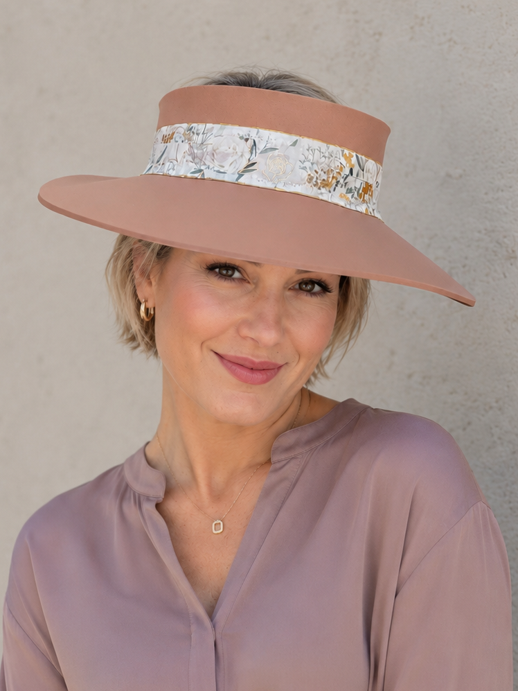 Woman wearing a wide-brimmed hat with floral band against a plain background
