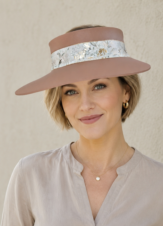 Woman wearing a wide-brimmed hat with a decorative band against a plain background