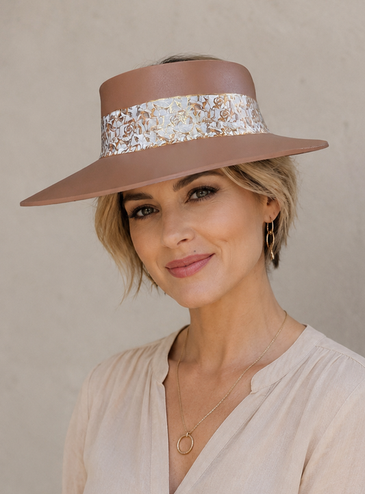 Woman wearing a beige hat with a decorative band against a neutral background