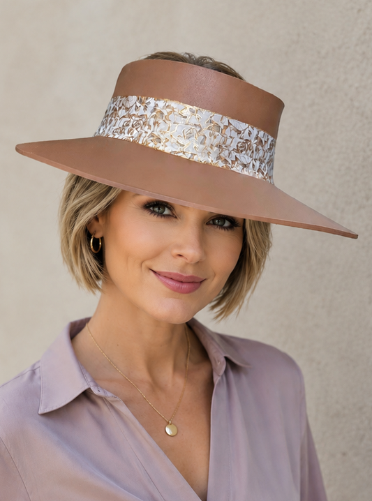 Woman wearing a wide-brimmed hat with a decorative band against a plain background