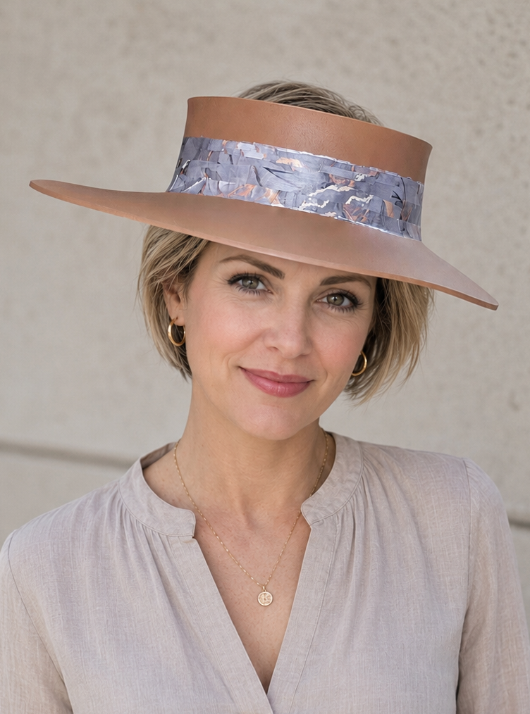 Woman wearing a wide-brimmed hat with a patterned band against a neutral background